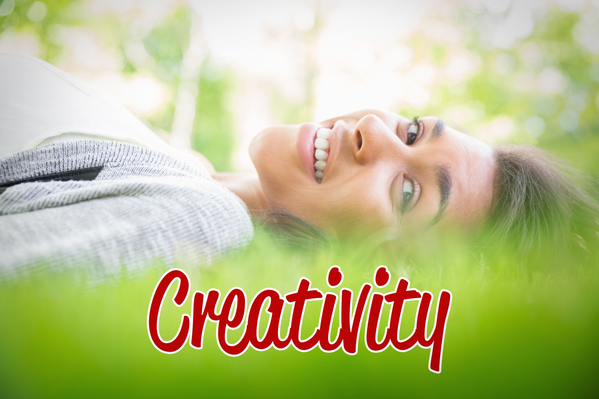 Creativity against pretty brunette lying on the grass